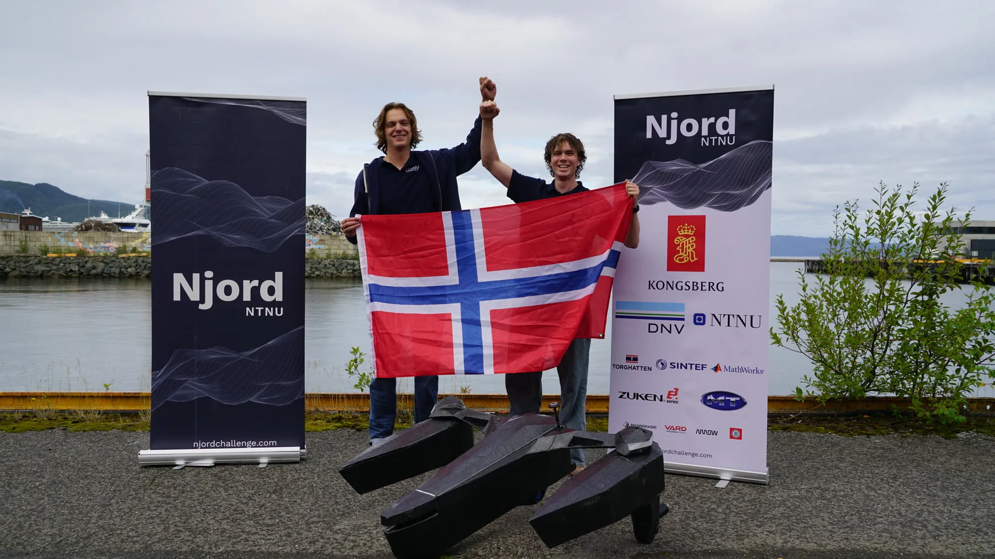 Ligmax team members holding a Norwegian flag behind the vessel at the Njord 2026 competition site